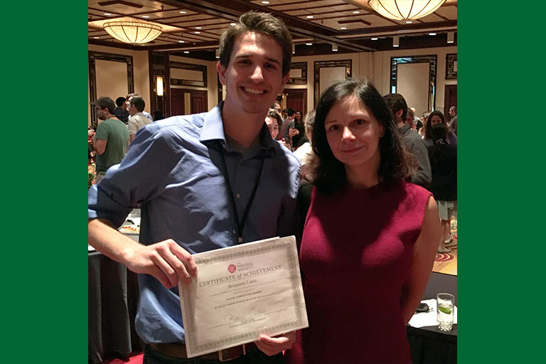 Benjamin Lantz holding his “Top Undergraduate Poster Presenter Award” at the Protein Society’s 31st Annual Symposium in Montreal, Canada, with Raluca Cadar, executive director.
