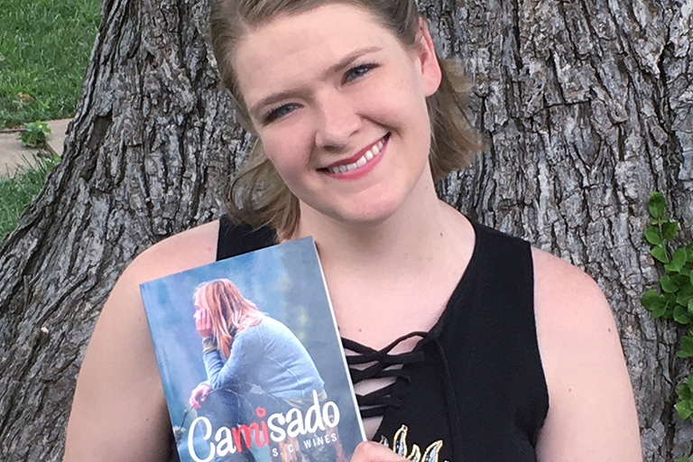 Greyhound graduate Sarah Wines with her first self-published book, “Camisado.”