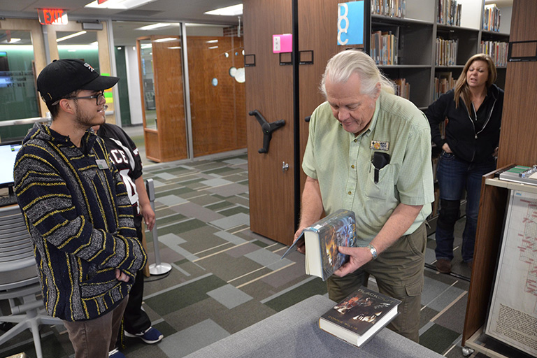 Kyle Garcia (left), a student worker, and Gene Bundy (right), Special Collections librarian, look at some of the books in the Jack Williamson Collection.