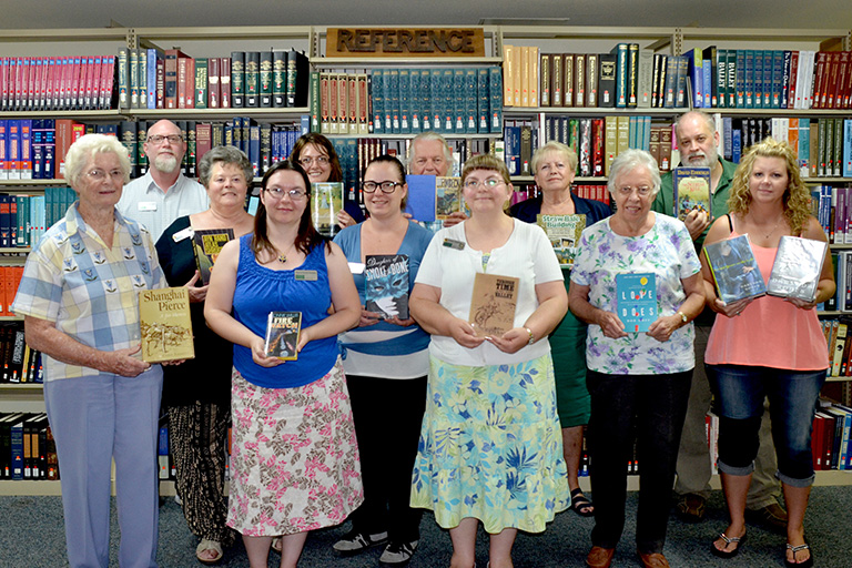 The Golden Library staff show the books they are reading this summer. First row (L-R): Melveta Walker, Regina Bouley Sweeten, Susan Asplund; second row (L-R): Lilah Gainey, Krystina Ferrari, Sherrye Burleson, Debbie Lang; third row (L-R): Christopher Haraughty, Heidi Greathouse, Gene Bundy, Michele Wood, Richard Baysinger.