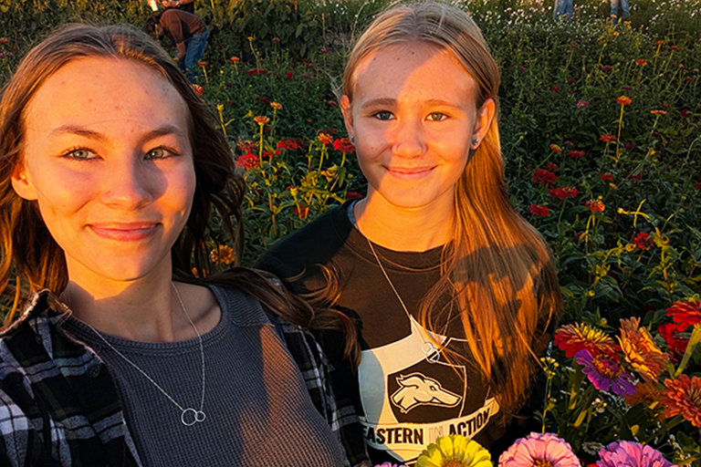 Marissa McCulloch and her younger sister pose in a flower garden.